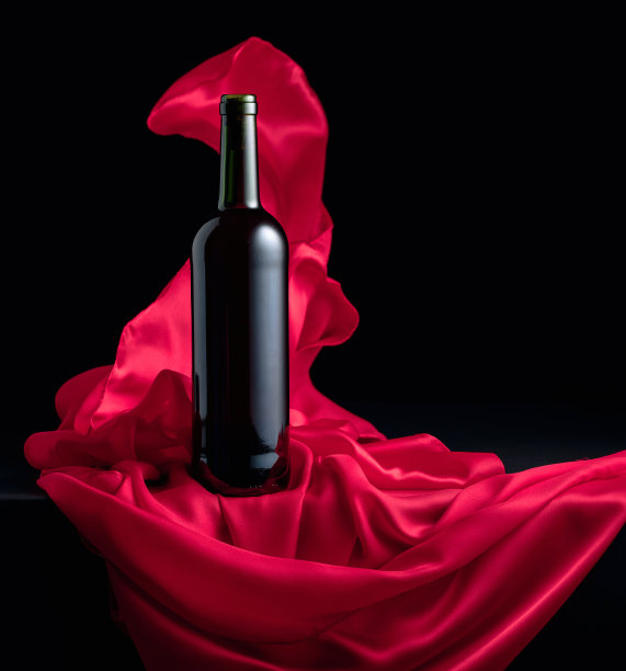 一瓶红酒和飘动的红布。图片下载