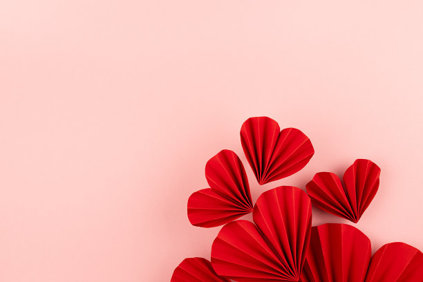 红纸肋心飞作为流动在柔和的浅粉色背景作为节日情人节背景，俯视图，复制空间。图片下载