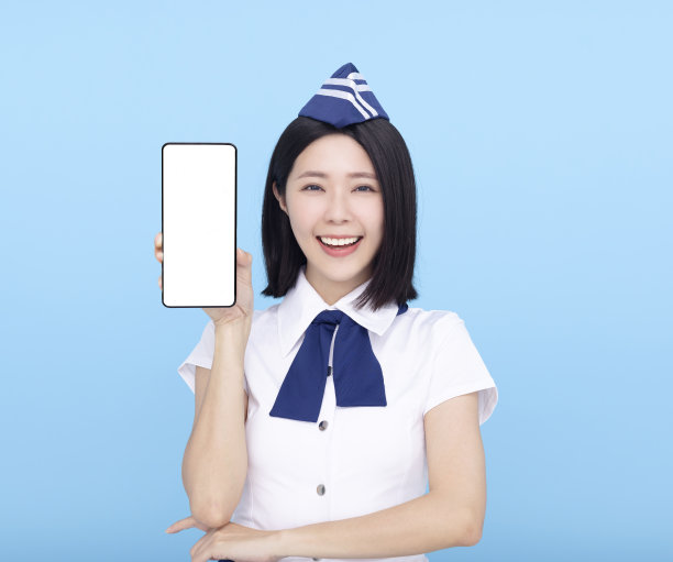 美丽的空姐展示手机与空白屏幕的蓝色背景图片下载