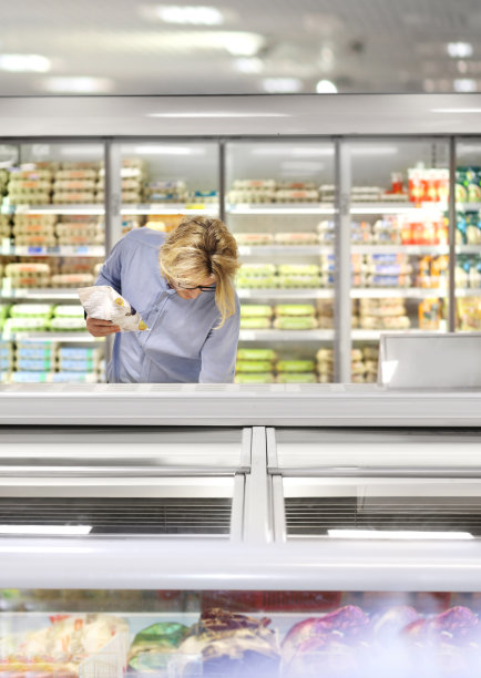 男人从超市冰柜选择冷冻食品并阅读产品信息图片下载