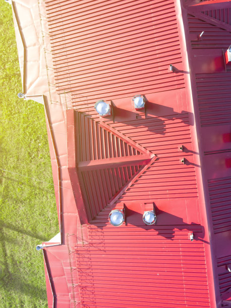 这是一架无人机在低空拍摄到的由铁聚合物板制成的建筑屋顶，屋顶上有通风扩散器和风管图片下载