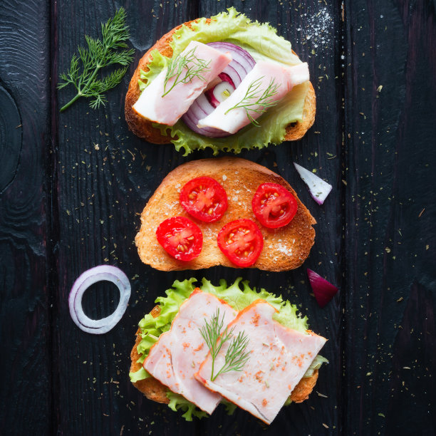 不同的三明治，黑色背景上有肉和蔬菜图片下载
