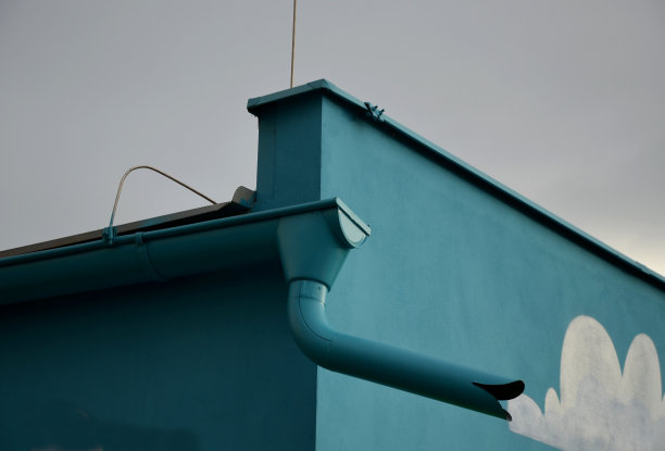 一栋被漆成蓝绿色的建筑，包括一条排水沟和一个喷水口。幼儿园的正面装饰着云朵图片下载