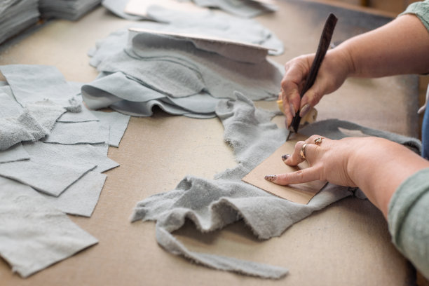 女工们的手正在车间的桌子上切割皮革。图片下载