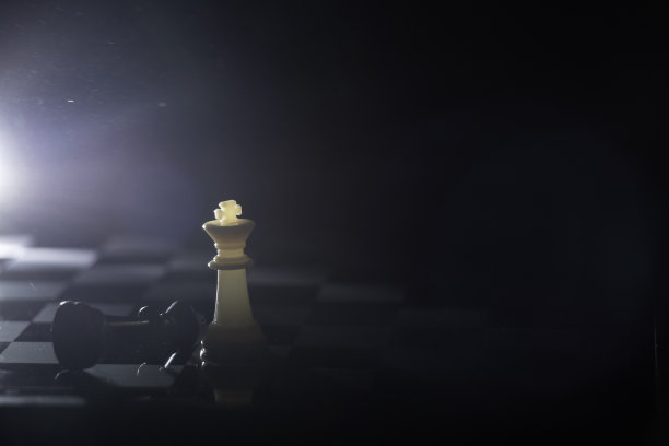 棋盘上的棋子在一个黑暗的房间里，由一盏灯照亮图片下载