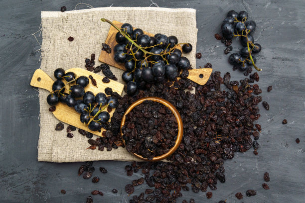 用木勺盛干黑葡萄干和新鲜成熟的葡萄。健康零食、膳食产品。平躺图片下载