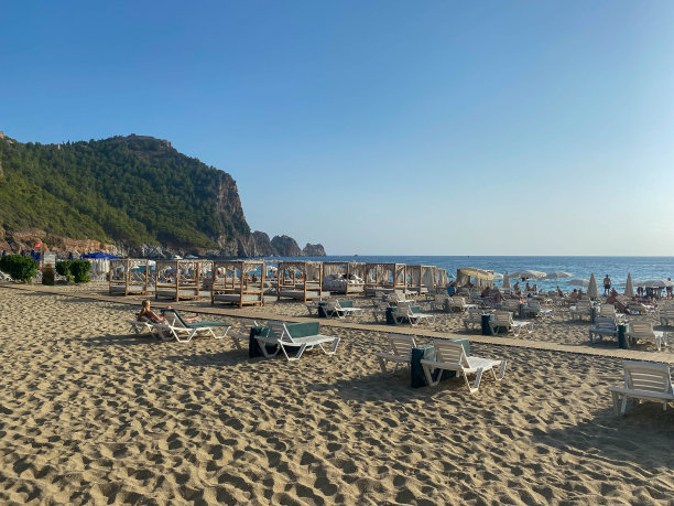 在一个温暖的热带东方南部乡村度假胜地，有山有海的沙滩上有许多日光浴躺椅图片下载