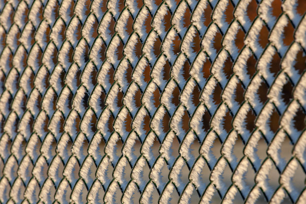 冬天的金属栅栏上覆盖着冰晶和阳光图片下载