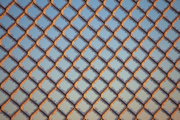 冬天的金属栅栏上覆盖着冰晶和阳光图片下载