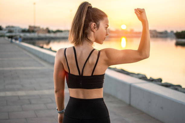在户外日落时在人行道上展示肌肉的强壮运动女性的背影图片下载