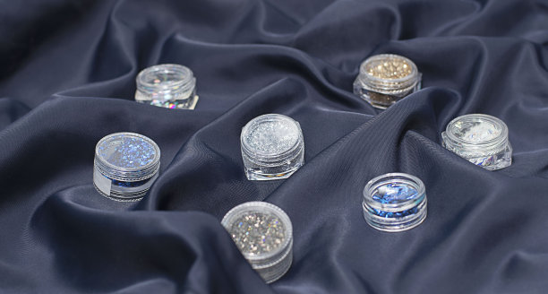蓝色丝绸面料上的指甲美甲设计的小罐子。图片下载