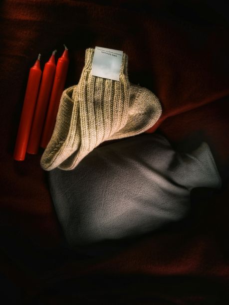 俯视图的红色蜡烛，一双羊毛袜子和一个热水瓶图片下载