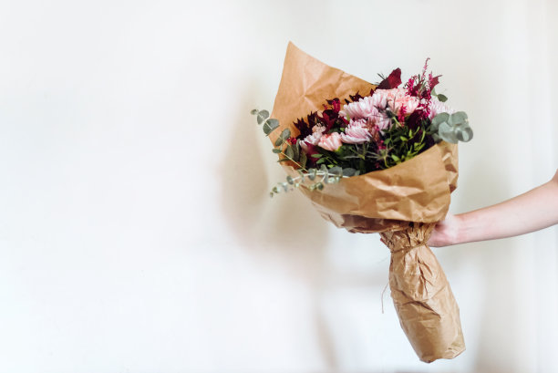 手捧一束用棕色纸包着的花图片下载