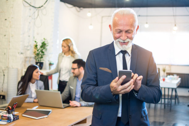 身着优雅西装的老年商人在办公室使用电话的肖像。图片下载