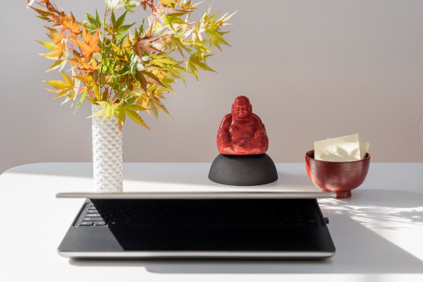 现代亚洲桌设置与枫叶，笑佛，笔记本电脑图片下载
