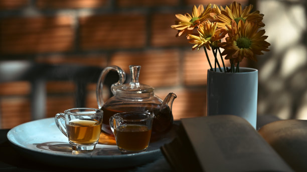 传统的茶具与杯子和茶壶在乡村木桌与树叶阴影和阳光的背景。图片下载