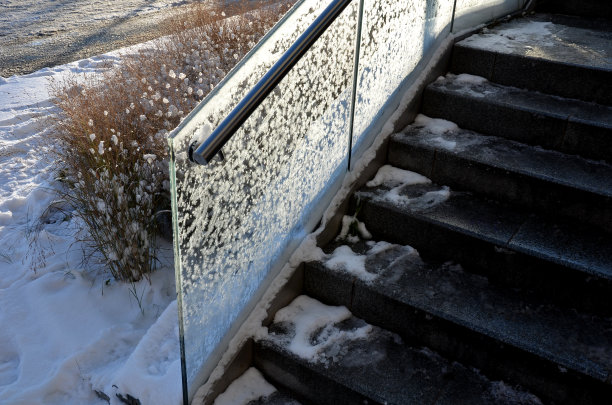 玻璃栏杆，金属手柄由抛光不锈钢管制成。阳台护栏单层胶合多层钢化安全玻璃。干草一排。霜白色糖霜不透明，抛光图片下载