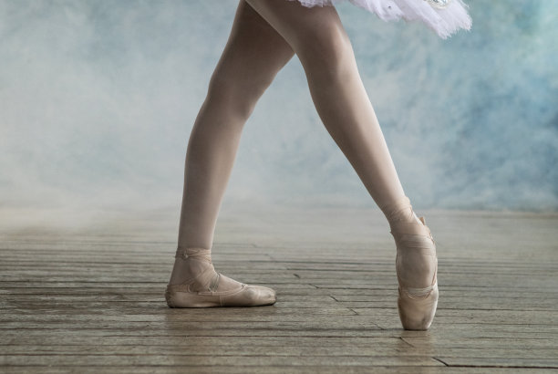 一名穿着白色芭蕾舞裙的职业芭蕾舞演员在有蓝色墙壁和烟雾的房间里跳舞图片下载