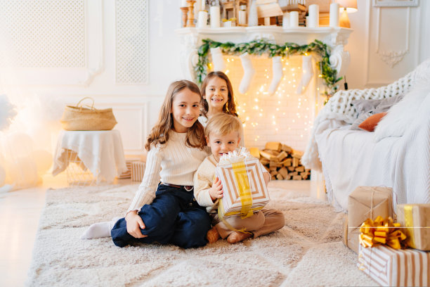 两个女孩和一个小男孩在一个装饰着圣诞节的房间里，盒子里装着礼物图片下载