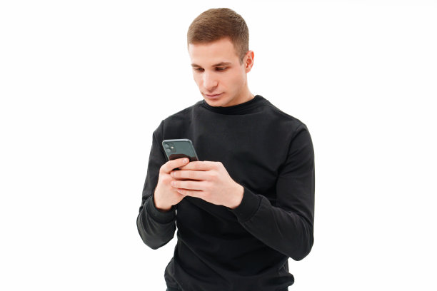 一个穿着黑衣的男人，手里拿着智能手机，背景是白色的。图片下载