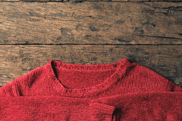 木制桌子上的红色毛衣冬季概念。图片下载