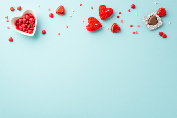 情人节的概念。顶部视图照片的心形碟子洒巧克力糖果和蜡烛在孤立的浅蓝色背景与复制空间图片下载