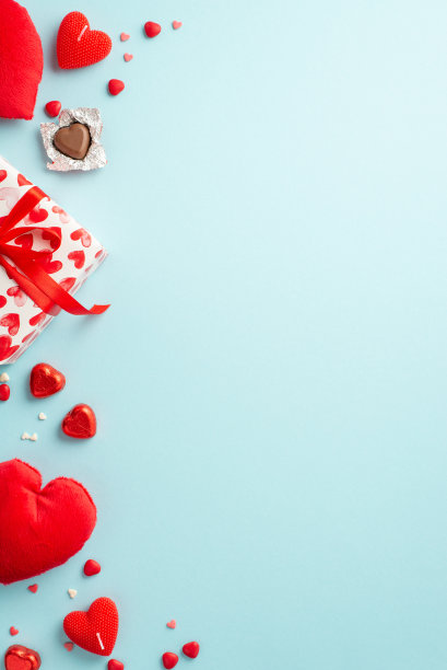 情人节的概念。顶部查看礼盒的垂直照片与丝带蝴蝶结心形毛绒玩具巧克力糖果蜡烛和洒在孤立的浅蓝色背景与复制空间图片下载