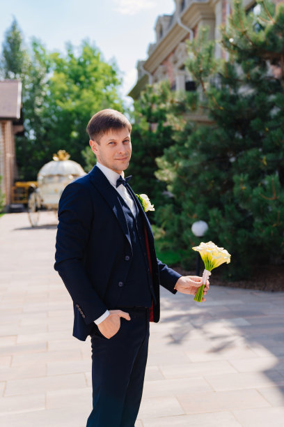 新郎穿着深蓝色的西装，上面有一枚胸花和一束马蹄莲。图片下载