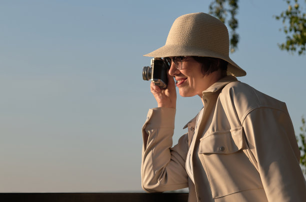 一名女游客戴着草帽，拿着老式相机在街上拍照图片下载