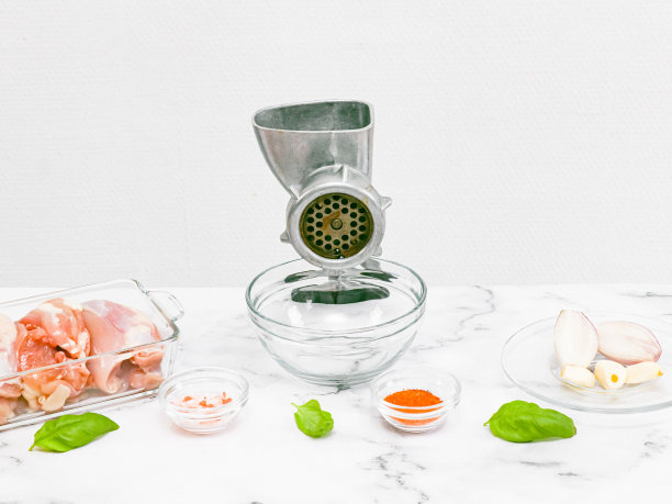 手工绞肉机，玻璃碗，去骨鸡腿，剥洋葱，大蒜放在大理石桌上。图片下载