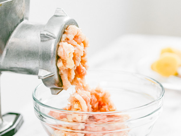 手工绞肉机，碎肉放在大理石桌上的玻璃盘子里图片下载