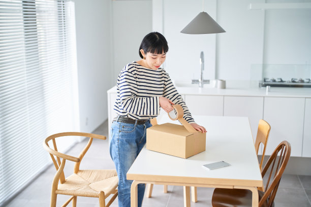 年轻女子把衣服装进纸板图片下载
