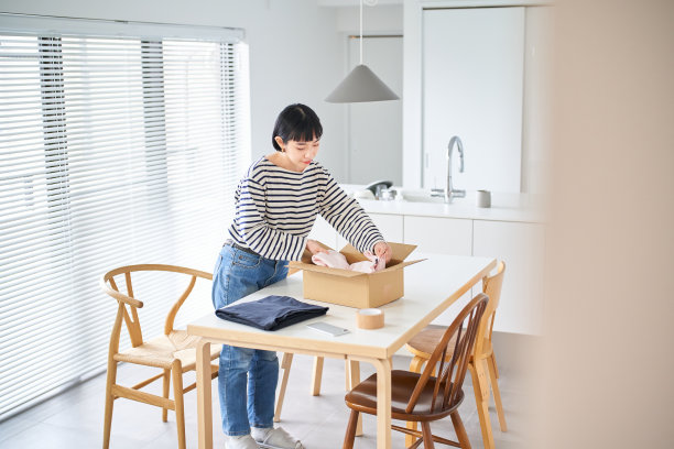 年轻女子把衣服装进纸板图片下载