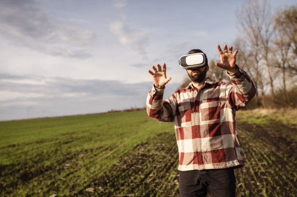 日落时分，年轻男子戴着虚拟现实眼镜站在麦田里图片下载