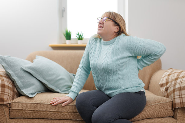 一名老年妇女在家里的沙发上遭受背部疼痛图片下载