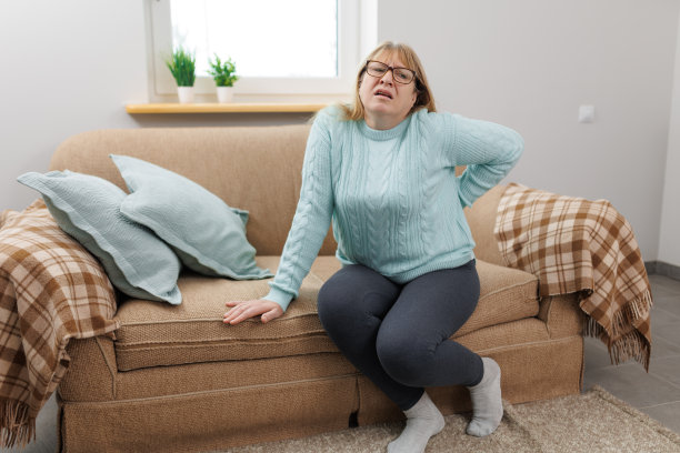 一名老年妇女在家里的沙发上遭受背部疼痛图片下载