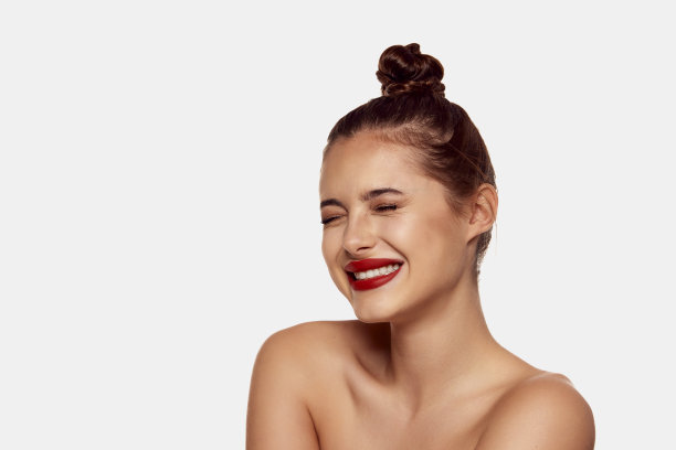 年轻美丽的女孩摆造型发髻和红唇孤立在白色背景。完美的微笑。美的概念，时尚美容，牙科护理图片下载