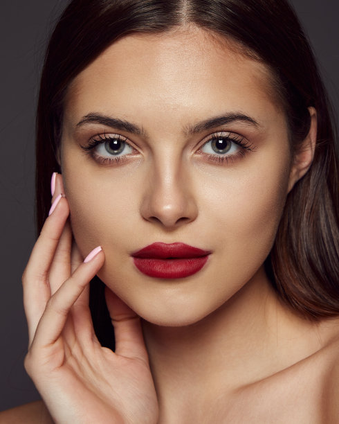 年轻美丽的女孩的特写肖像，红唇看着相机，在深灰色的背景上摆出孤立的姿势。美、时尚和美容的概念图片下载