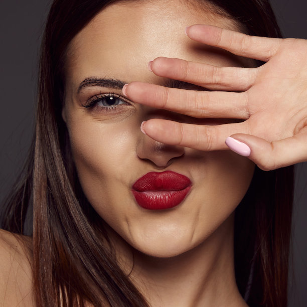 年轻美丽的黑发女孩的特写肖像，红唇孤立在深灰色的背景。亲吻。美、时尚和美容的概念图片下载
