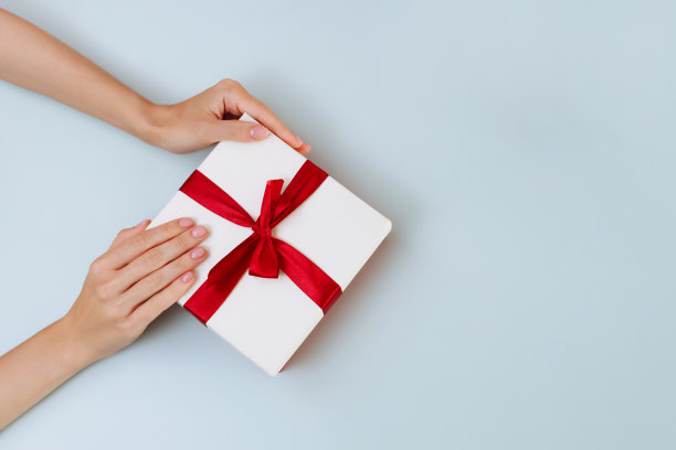 女子手中握着一个白色带红色的蝴蝶结图片下载