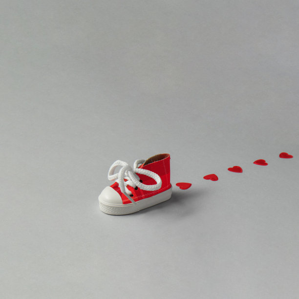 情人节创意。运动鞋在灰色背景上留下心形印记。极简爱走概念。图片下载
