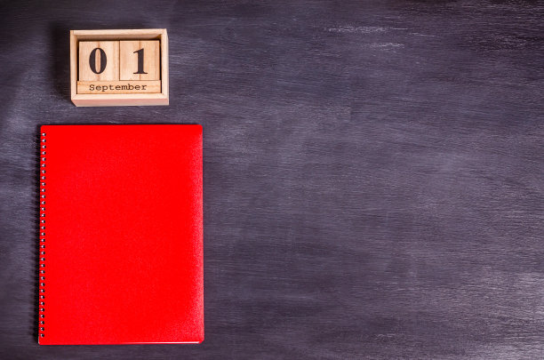红色的笔记本和黑色背景的9月1日木制日历图片下载