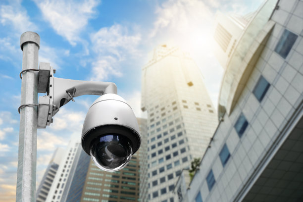 现代公共闭路电视摄像机在电杆模糊建筑背景。全天监控的录音摄像头。监视概念和带有复制空间的监视。图片下载