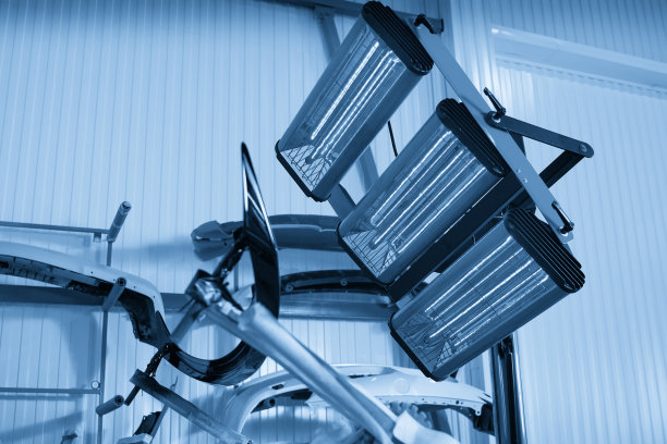 在保险杠上涂抹腻子和油漆后，在车身部件的专业箱灯下进行喷漆和烘干图片下载