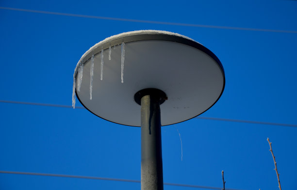 板式路灯。在冰柱的边缘装饰了一个圆形的灯。灰色的柱子，蓝色的天空图片下载