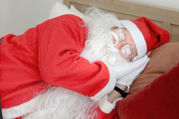 圣诞老人睡得舒舒服服的，年长的长胡子老人穿着圣诞老人服装在辛苦工作了很久之后打了个盹，圣诞寒假快乐。图片下载