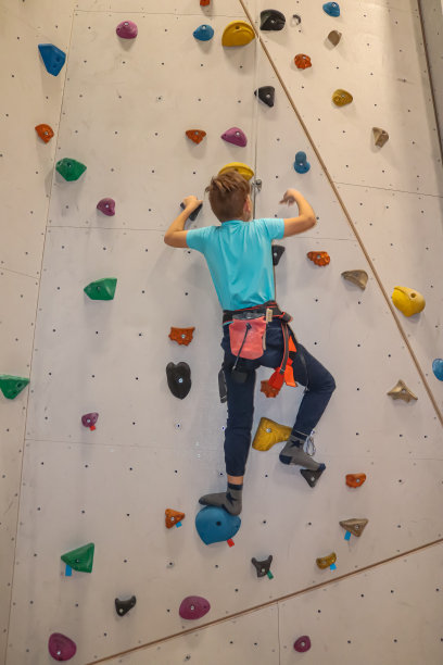小男孩在室内攀岩墙上用顶绳攀爬图片下载
