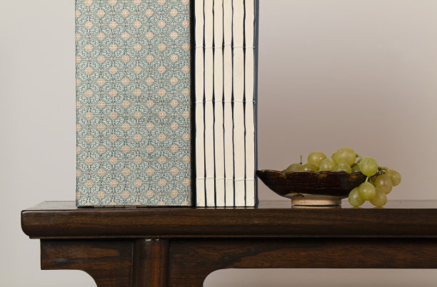 白墙上的木桌上摆放着中国古董盘上的白葡萄和中国传统书籍图片下载