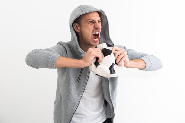 英俊的球员男子踢足球抱着足球背景指向不满和沮丧的相机，生气和愤怒的你图片下载