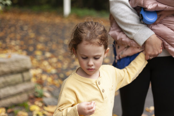 一个可爱美丽的小女孩的特写肖像，戴着眼镜，牵着她妈妈的手。可爱的家庭秋天户外照片图片下载
